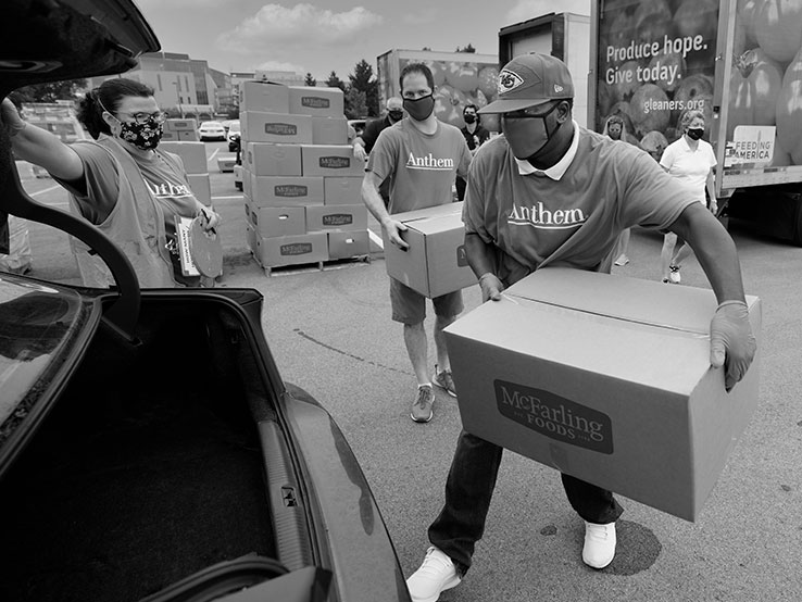 Two man loading boxes into a car trunk