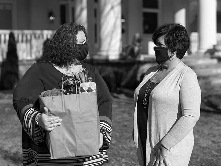 Two women standing in front of a house talking to each other