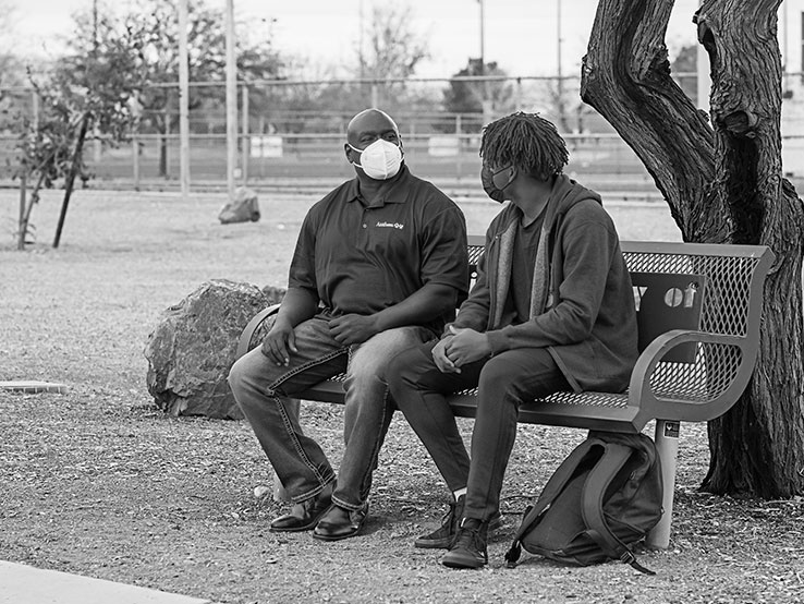 Two people sitting on a park bench talking to each other